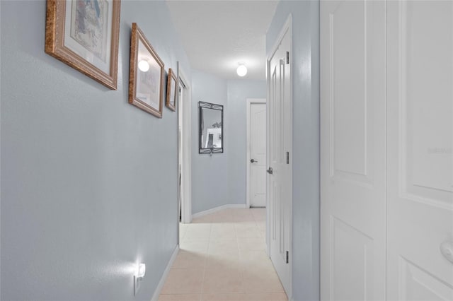 hallway with a textured ceiling and light tile patterned flooring