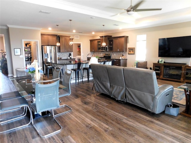 living room featuring ceiling fan, dark hardwood / wood-style floors, a fireplace, and crown molding