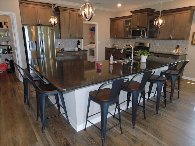 kitchen featuring appliances with stainless steel finishes, dark hardwood / wood-style flooring, a spacious island, and a notable chandelier