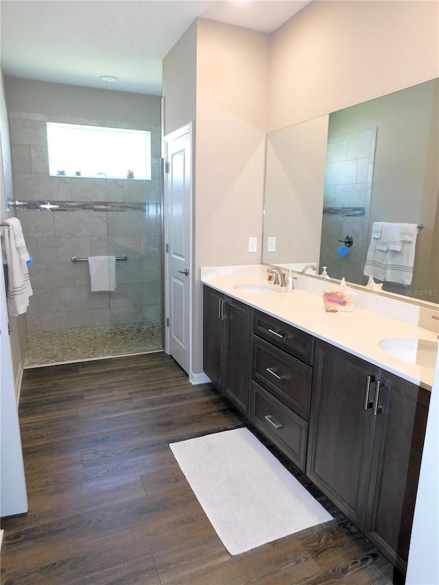 bathroom featuring hardwood / wood-style flooring, vanity, and tiled shower