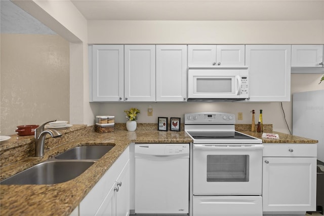 kitchen featuring white cabinets, dark stone countertops, sink, and white appliances