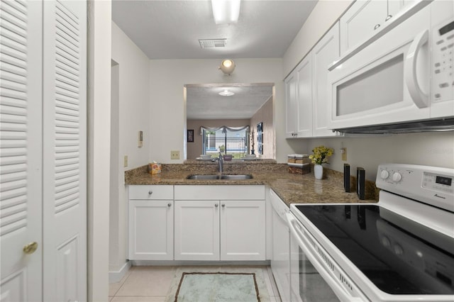 1428 SW 25th Pl, Gainesville, FL 32608 - kitchen featuring white appliances, a sink, white cabinets, light tile patterned floors, and dark stone counters