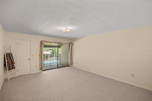 spare room featuring a textured ceiling and light colored carpet