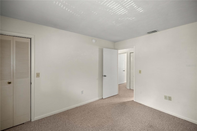 unfurnished bedroom featuring a closet and light colored carpet