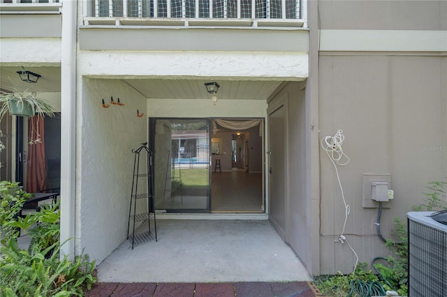 view of exterior entry featuring a balcony and central air condition unit