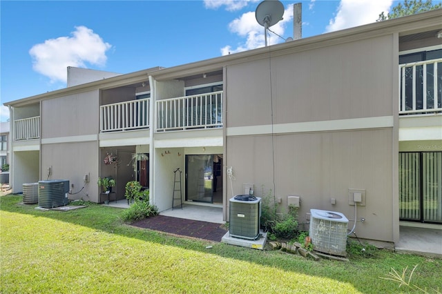 back of house featuring a balcony, central AC unit, and a yard