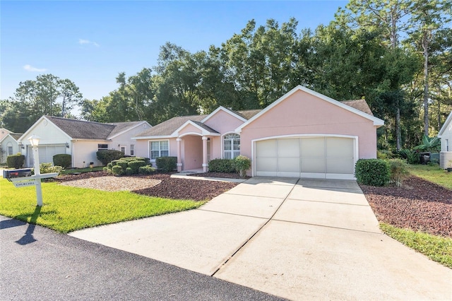 ranch-style house featuring a garage, a front yard, driveway, and stucco siding