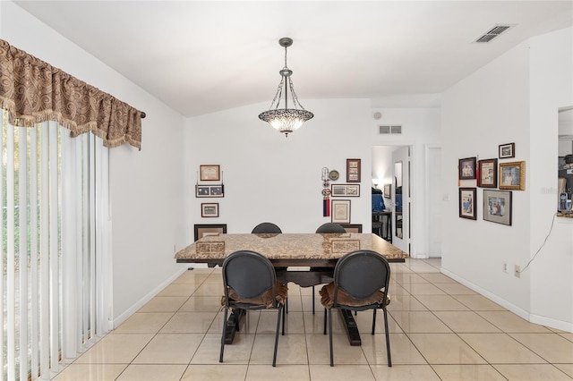 dining room featuring a notable chandelier, light tile patterned flooring, and lofted ceiling