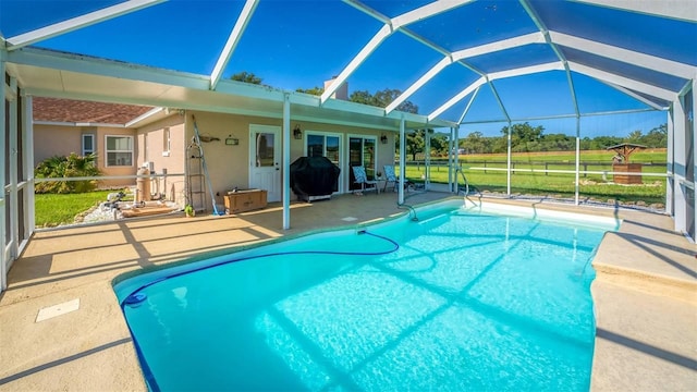 view of pool with a patio, glass enclosure, and a grill