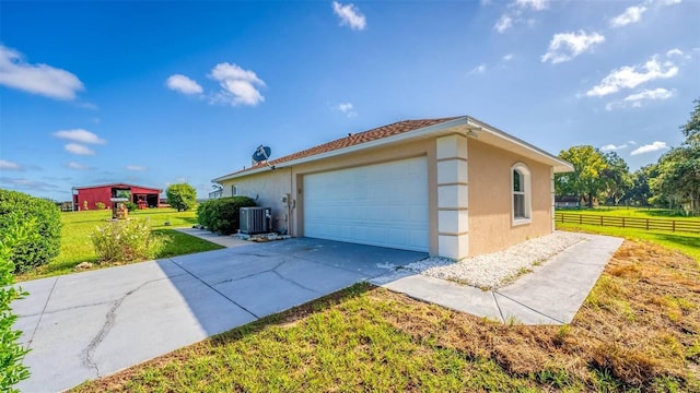 view of side of property featuring a lawn, a garage, and central air condition unit