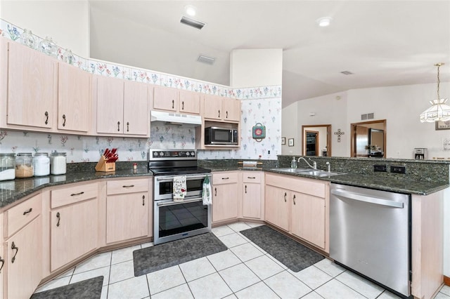 kitchen with light brown cabinets, lofted ceiling, sink, decorative light fixtures, and stainless steel appliances