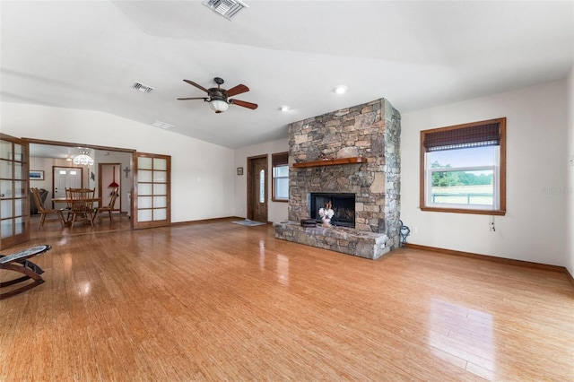 unfurnished living room featuring a healthy amount of sunlight, lofted ceiling, a fireplace, and light hardwood / wood-style flooring