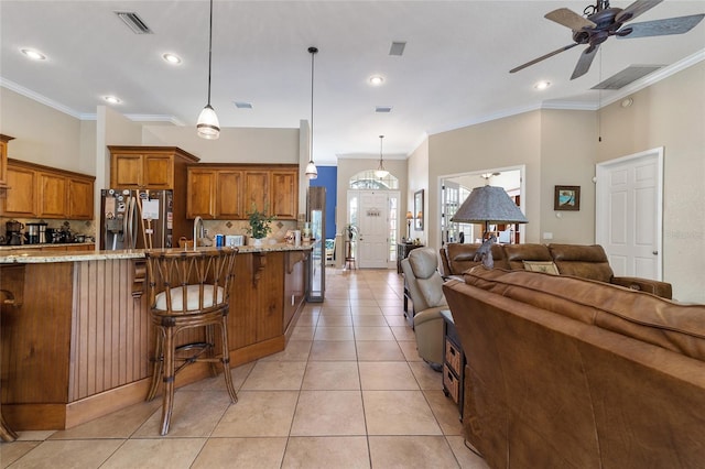 kitchen featuring decorative backsplash, light stone counters, light tile patterned floors, stainless steel fridge, and ceiling fan