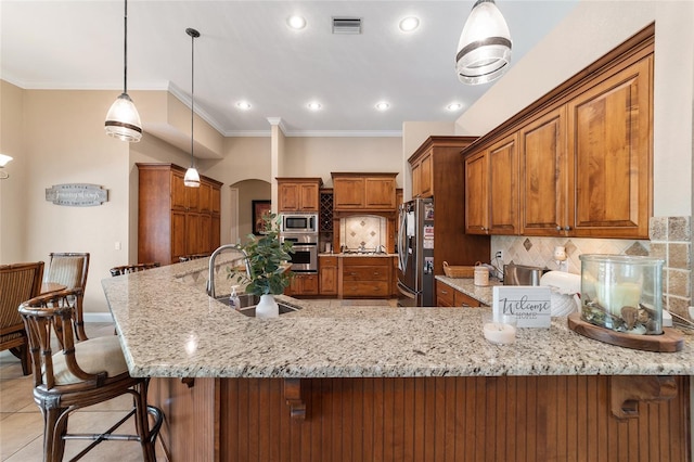 kitchen featuring a kitchen breakfast bar, backsplash, pendant lighting, appliances with stainless steel finishes, and sink