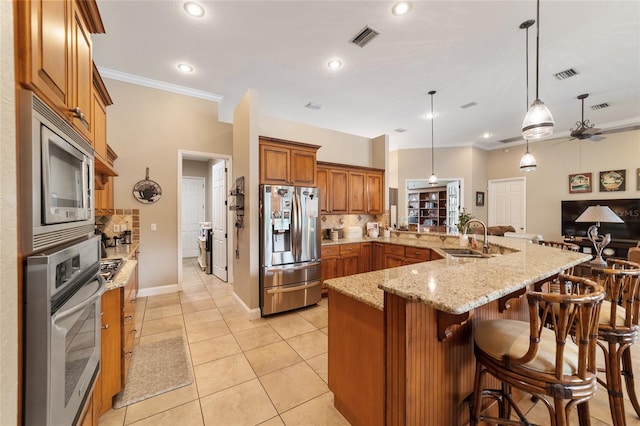 kitchen featuring stainless steel appliances, decorative backsplash, a kitchen bar, pendant lighting, and light tile patterned floors