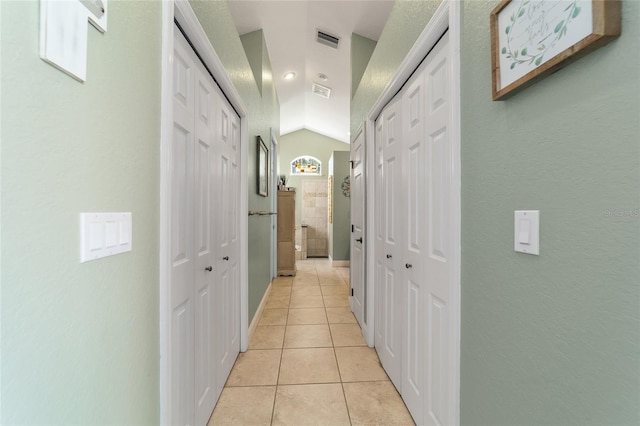 hall with lofted ceiling and light tile patterned floors