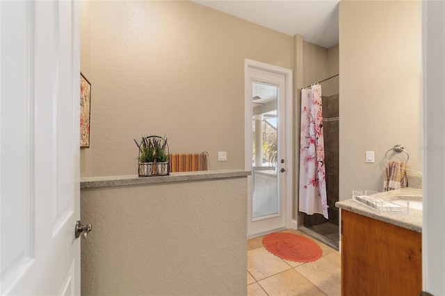 bathroom featuring tile patterned flooring, walk in shower, and vanity