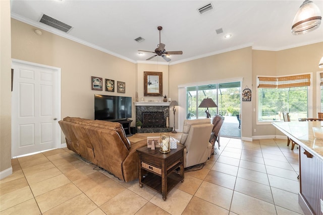 living room featuring light tile patterned flooring, crown molding, a premium fireplace, and ceiling fan