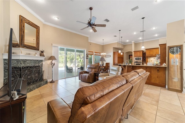 living room featuring ceiling fan, light tile patterned floors, crown molding, and a premium fireplace