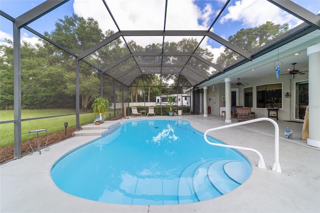 view of pool with ceiling fan, a yard, a patio area, and glass enclosure