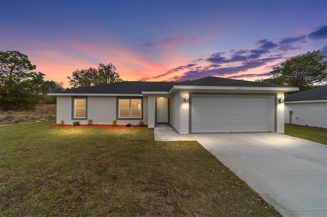 ranch-style house with a garage and a lawn