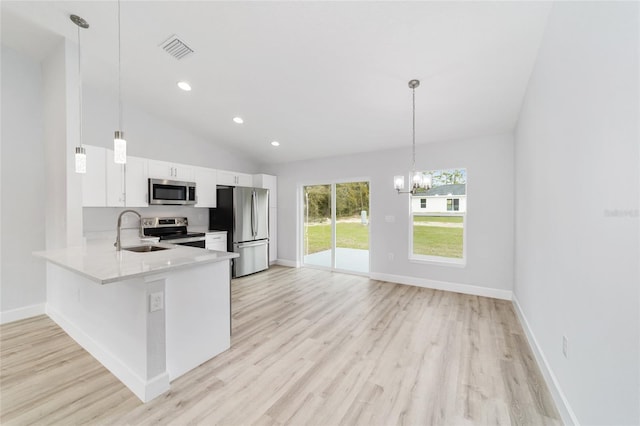 kitchen featuring light wood-type flooring, appliances with stainless steel finishes, pendant lighting, and white cabinets