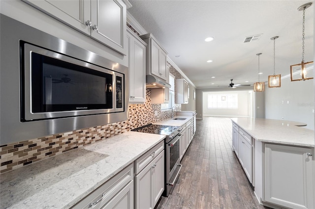 kitchen with light stone countertops, sink, dark hardwood / wood-style floors, decorative backsplash, and appliances with stainless steel finishes