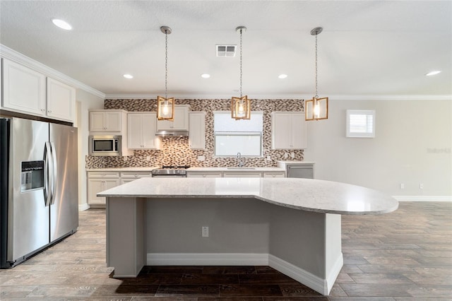 kitchen with stainless steel appliances, sink, wood-type flooring, a center island, and white cabinetry