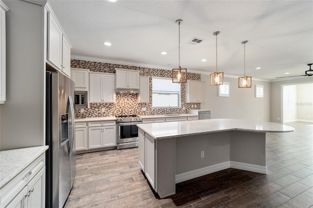 kitchen with white cabinetry, a kitchen island, ornamental molding, and appliances with stainless steel finishes