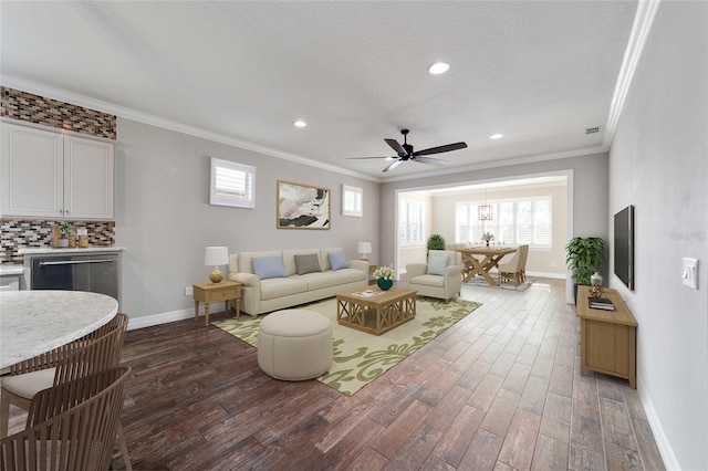 living room featuring ceiling fan, dark hardwood / wood-style flooring, ornamental molding, and a textured ceiling