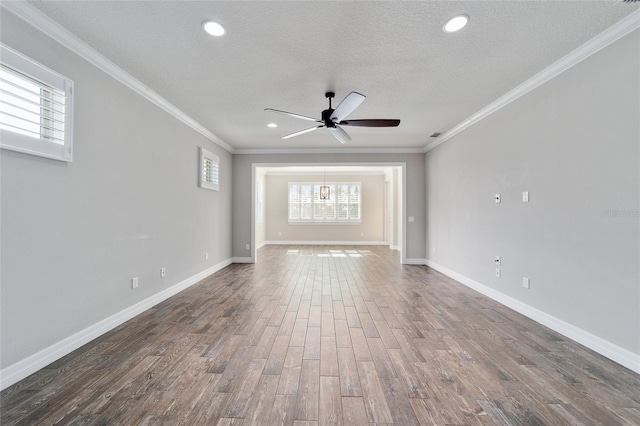 unfurnished living room with a textured ceiling, ceiling fan with notable chandelier, dark hardwood / wood-style flooring, and crown molding