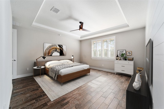 bedroom with a tray ceiling, ceiling fan, and dark hardwood / wood-style flooring