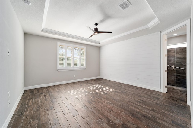 spare room with ceiling fan, dark hardwood / wood-style flooring, a textured ceiling, and a tray ceiling