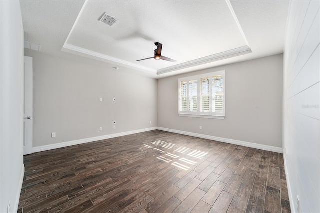 unfurnished room featuring a textured ceiling, a raised ceiling, and dark wood-type flooring