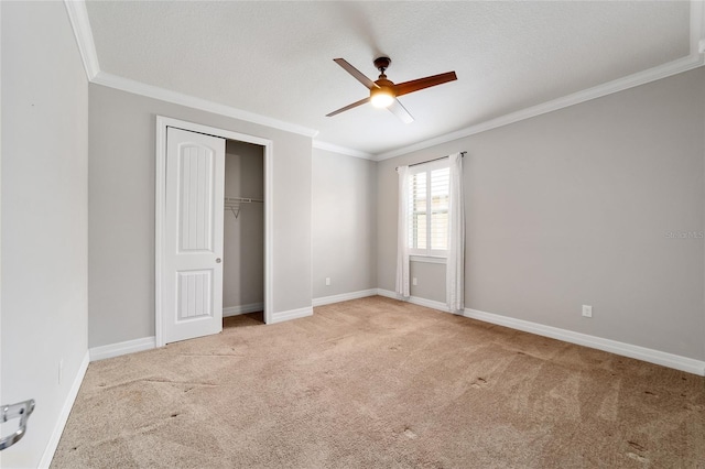 unfurnished bedroom with ceiling fan, light colored carpet, a textured ceiling, and ornamental molding