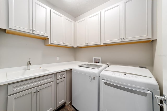 laundry room featuring sink, cabinets, dark wood-type flooring, separate washer and dryer, and a textured ceiling