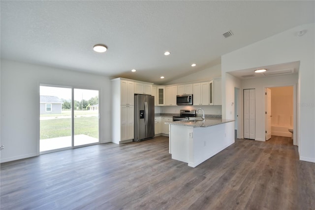 kitchen featuring hardwood / wood-style floors, stainless steel appliances, kitchen peninsula, and vaulted ceiling