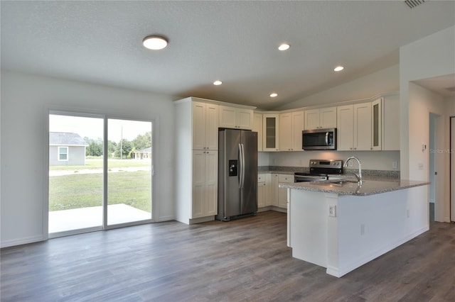 kitchen with vaulted ceiling, appliances with stainless steel finishes, dark hardwood / wood-style flooring, white cabinetry, and kitchen peninsula