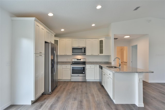 kitchen featuring light wood-type flooring, light stone counters, kitchen peninsula, sink, and appliances with stainless steel finishes