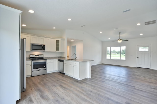 kitchen with vaulted ceiling, appliances with stainless steel finishes, light hardwood / wood-style floors, sink, and kitchen peninsula