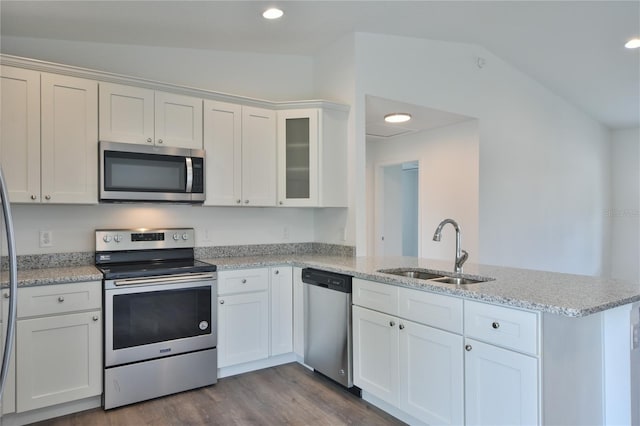 kitchen featuring appliances with stainless steel finishes, kitchen peninsula, and vaulted ceiling