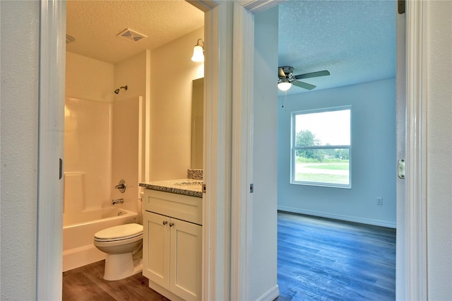 full bathroom featuring vanity, shower / washtub combination, wood-type flooring, toilet, and ceiling fan