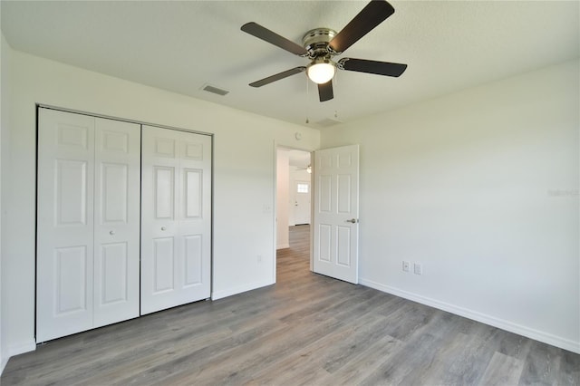 unfurnished bedroom with hardwood / wood-style floors, ceiling fan, and a closet