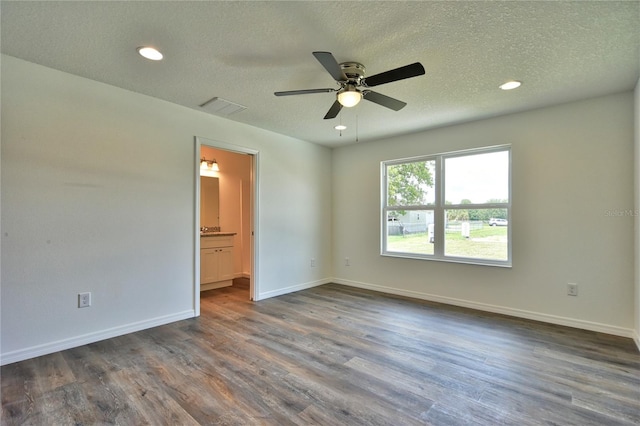 spare room with dark hardwood / wood-style flooring, ceiling fan, and a textured ceiling