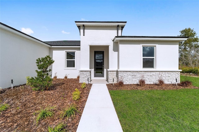 doorway to property featuring stone siding, a yard, and stucco siding