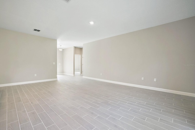 empty room featuring baseboards, visible vents, and wood finished floors