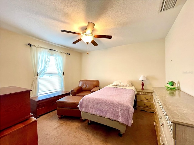 bedroom with a textured ceiling, dark carpet, and ceiling fan