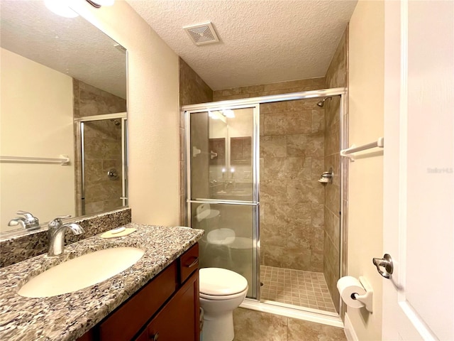 bathroom featuring toilet, walk in shower, tile patterned flooring, vanity, and a textured ceiling