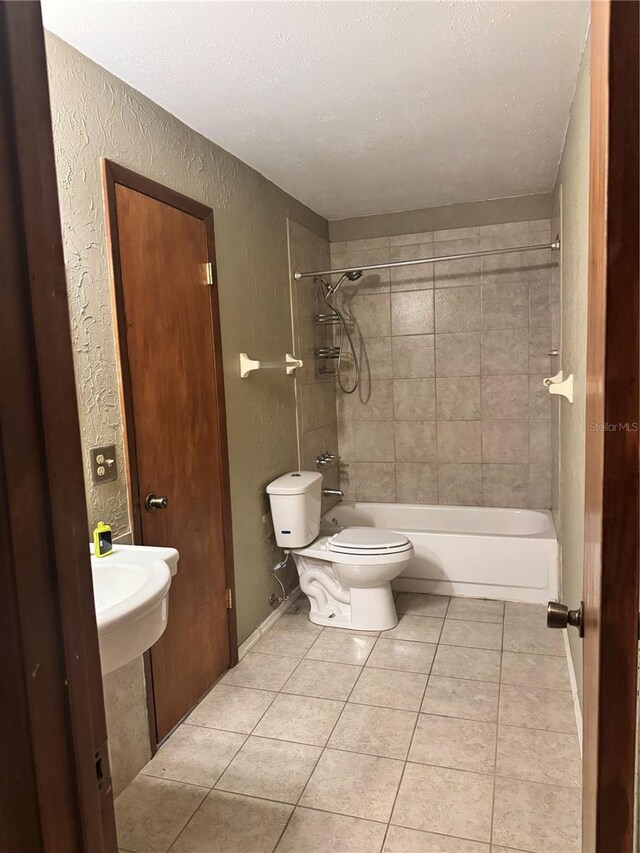 bathroom with tile patterned floors, toilet, a textured ceiling, and a textured wall