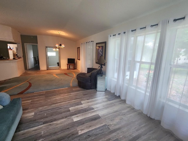 living room with wood-type flooring, plenty of natural light, an inviting chandelier, and vaulted ceiling